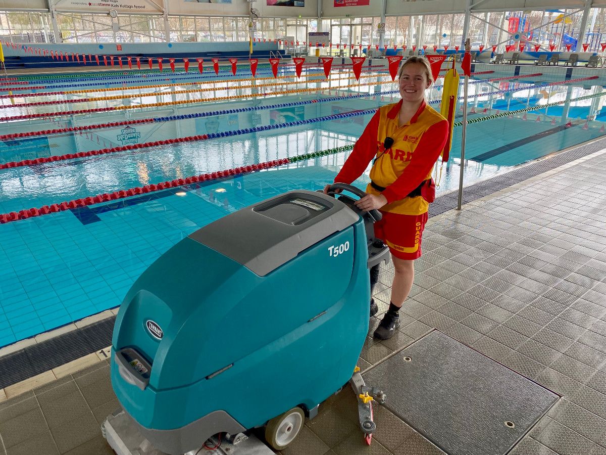 A young woman lifeguard operating a tile cleaning machine