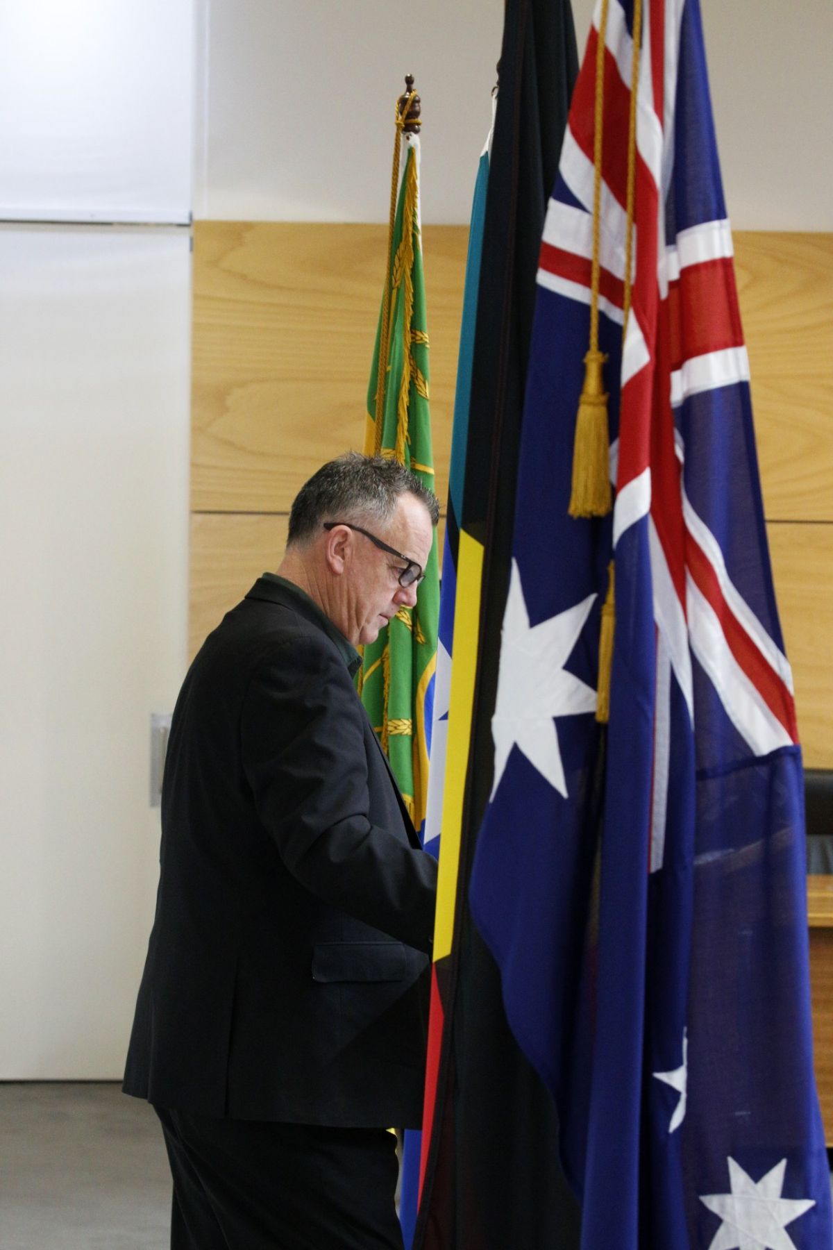 Dallas Tout standing at podium with flags on either side