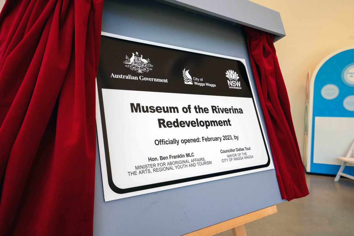 Two men and First Nations woman unveiling plaque