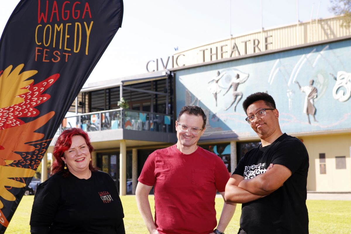 Woman and two men standing next to Comedy Fest banner with Civic Theatre in background