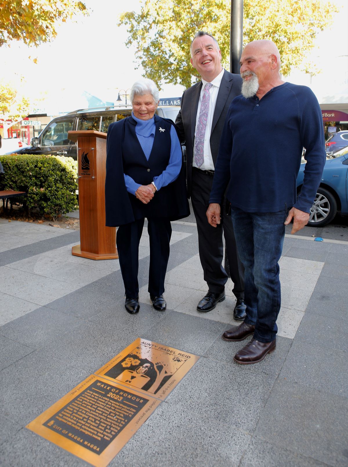 three people standing around a recently unveiled plaque