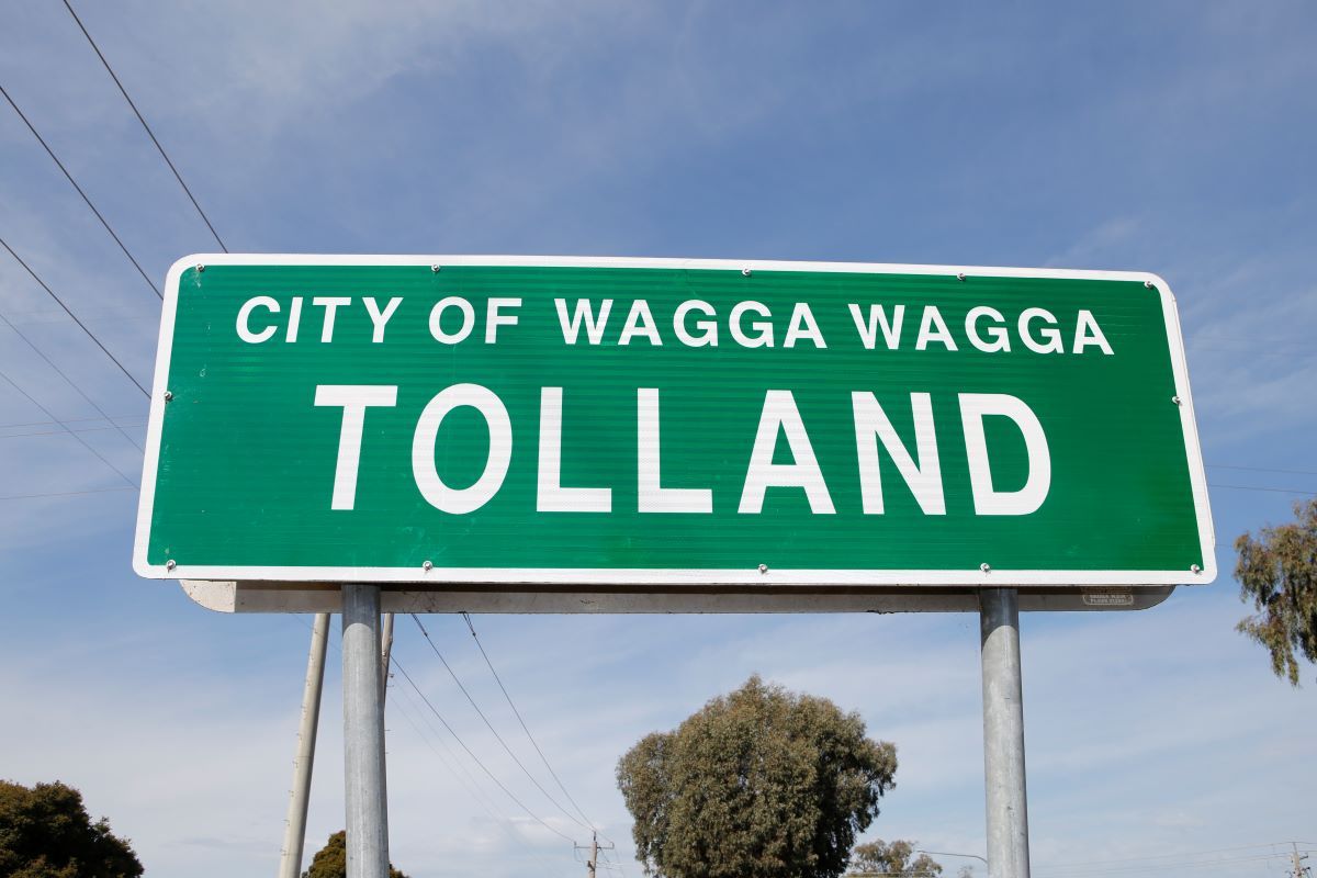 A green street sign with the words 'City of Wagga Wagga' across the top in white. Underneath is the word 'Tolland' in large white capital letters. 