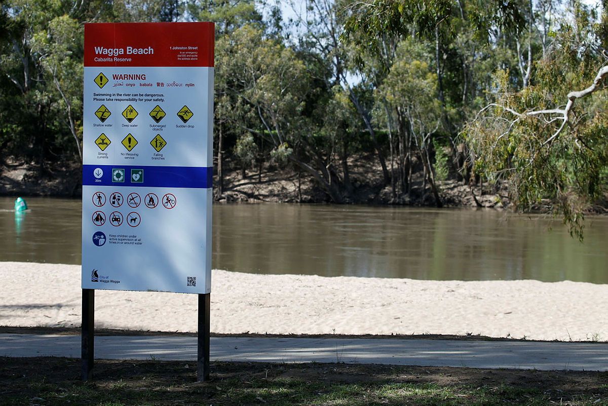 A warning sign at the Wagga Beach, the river is in the background. 