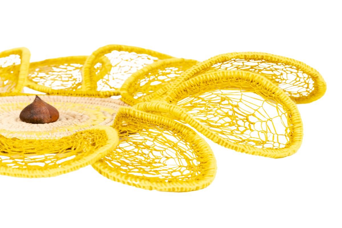 Yellow flower made from woven materials. On a white background. 