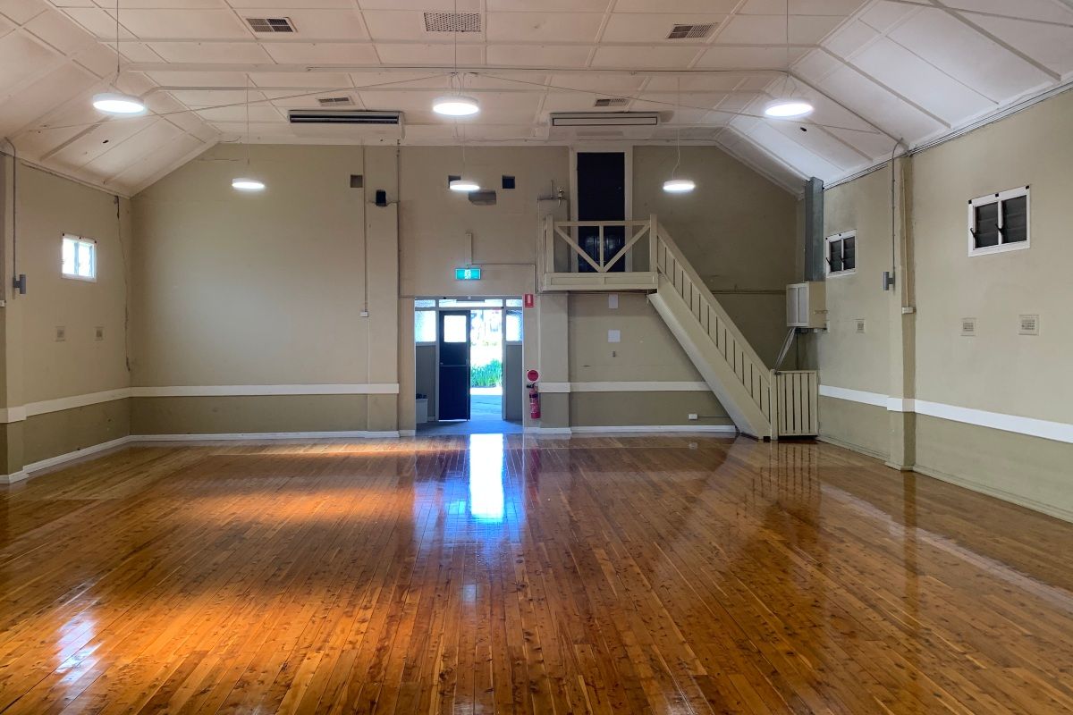 The inside of a community hall. It is empty as the walls have been painted a beige colour, and the floor boards have been restored so they are polished and shiny. 