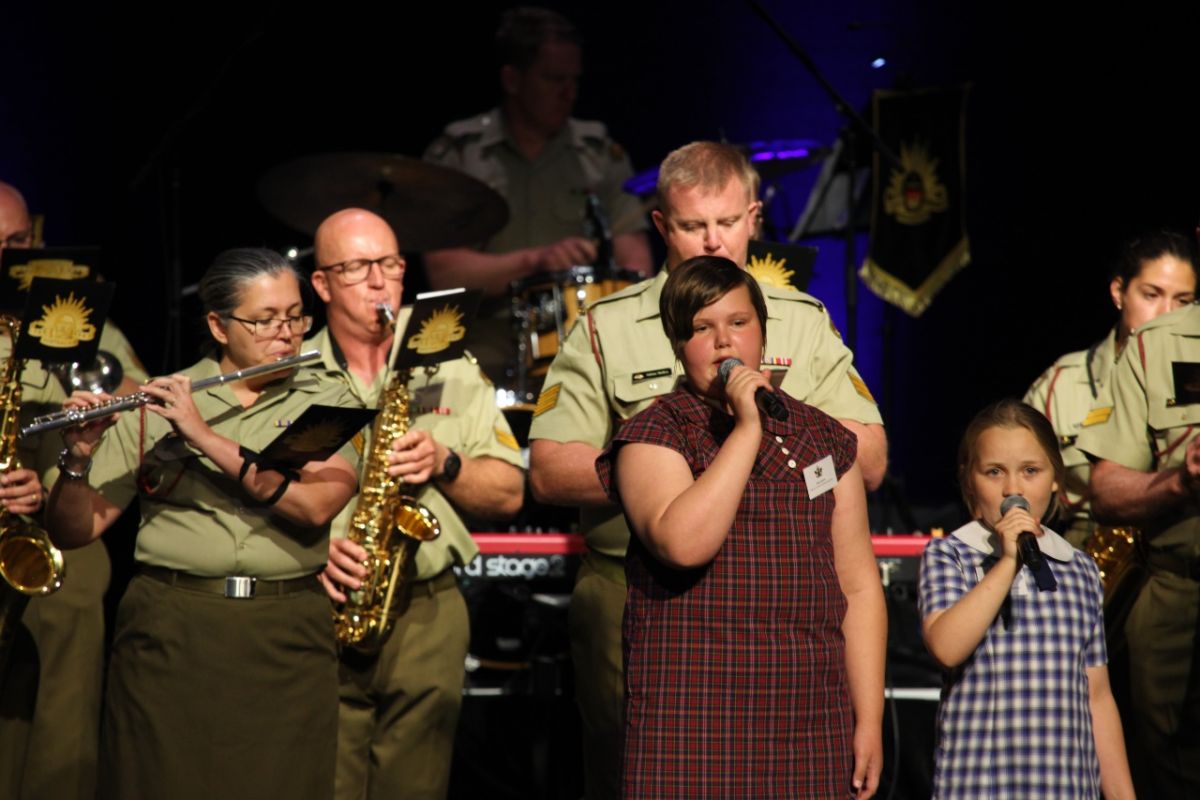 Young school students in uniforms singing on stage at the Civic Theatre.