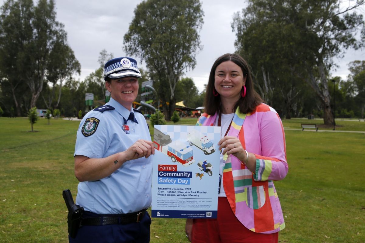 Female police inspector and female council staff member holding promotional poster for family safety event