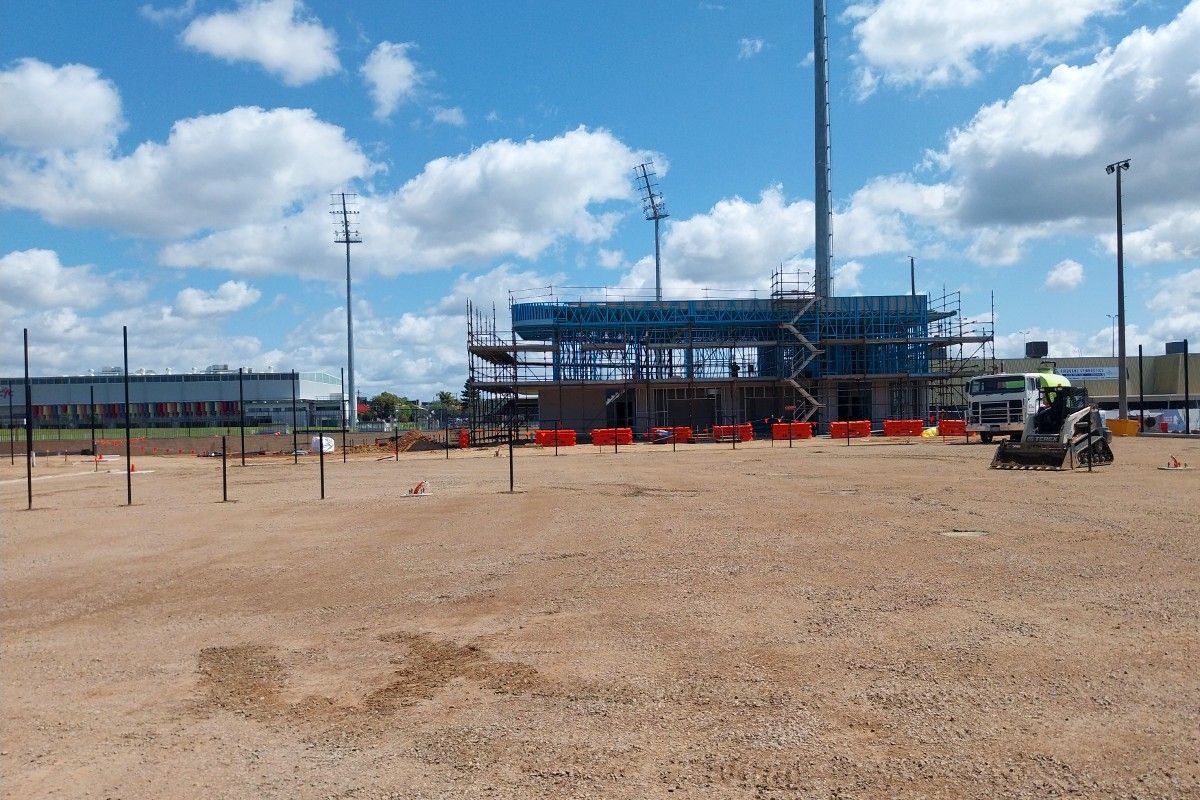 Construction site with steel framework of new clubhouse building in the background.