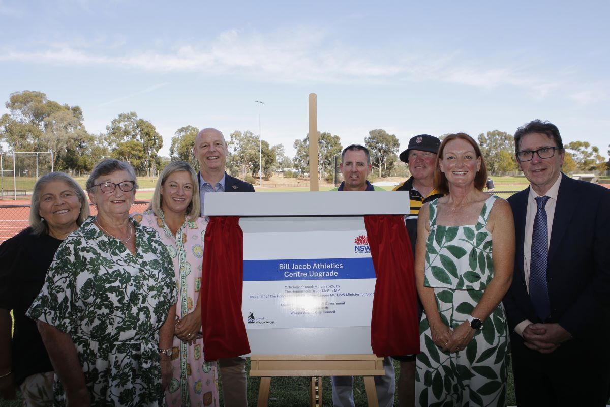 A group of men and women at an the official opening of the athletics centre. 