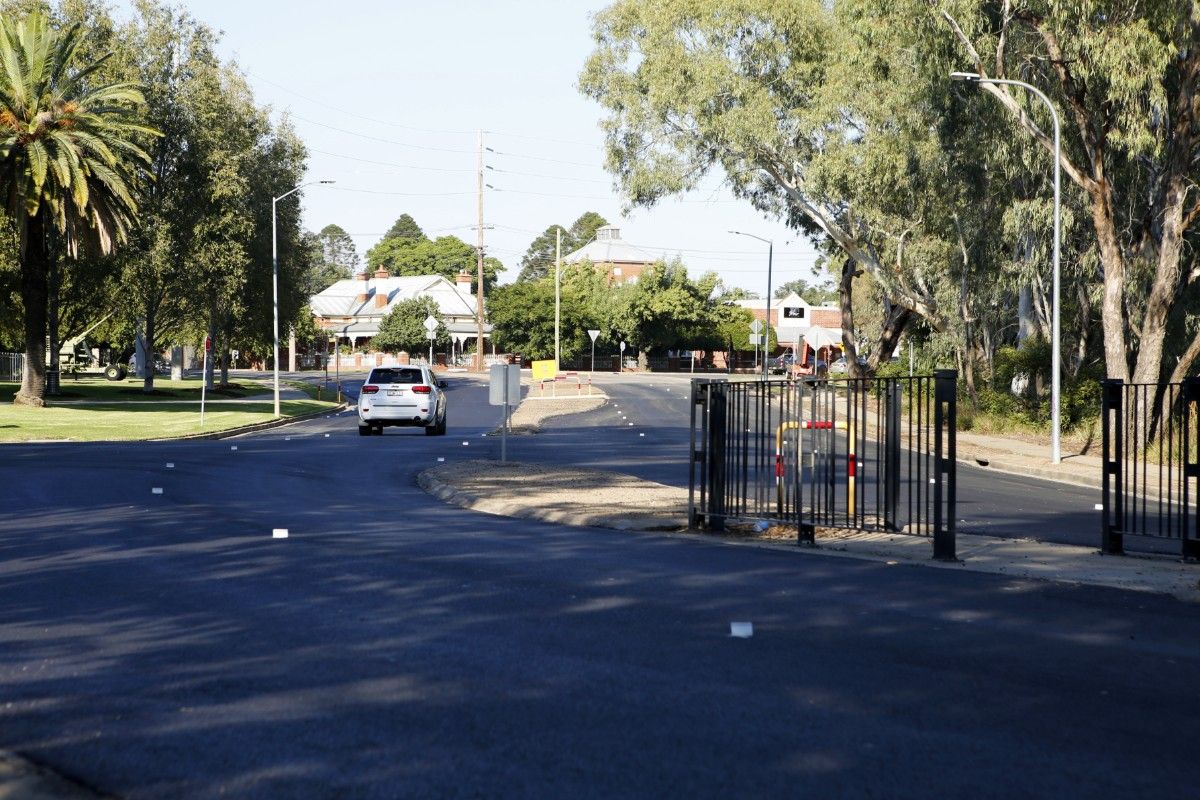 Vehicle travelling along newly rehabilitated road, with a pedestrian island in the middle of the road.
