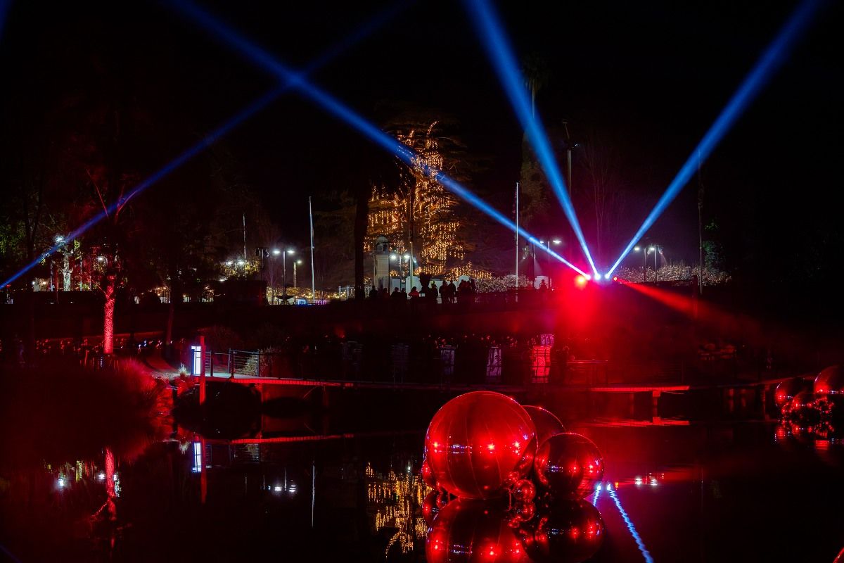 Large, mirrored spheres floating on the water of a lagoon and bathed in and reflecting red light.