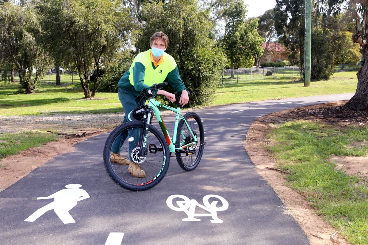 Man leaning on bike on shared pathway