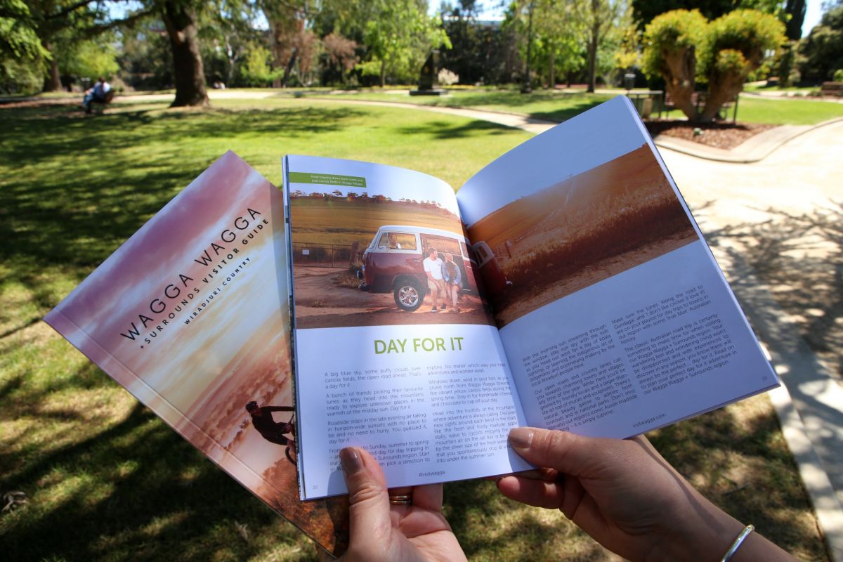 Open pages of visitor guide and close copy being held in hands