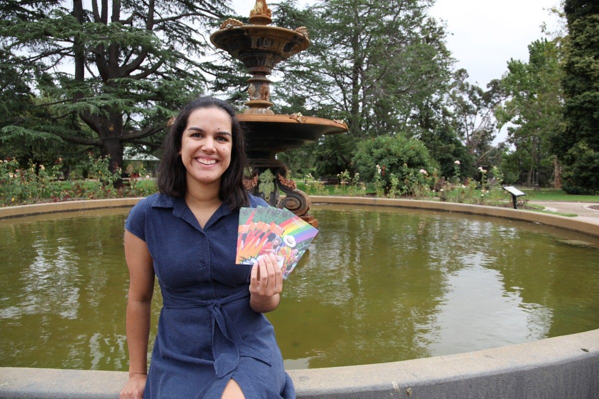 Woman in front of a fountain holding a sheaf of booklets