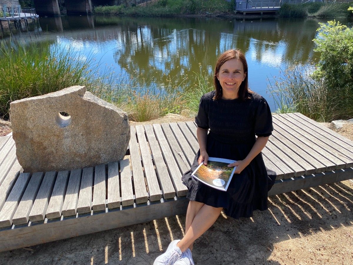 A woman sitting on a bench beside a lagoon