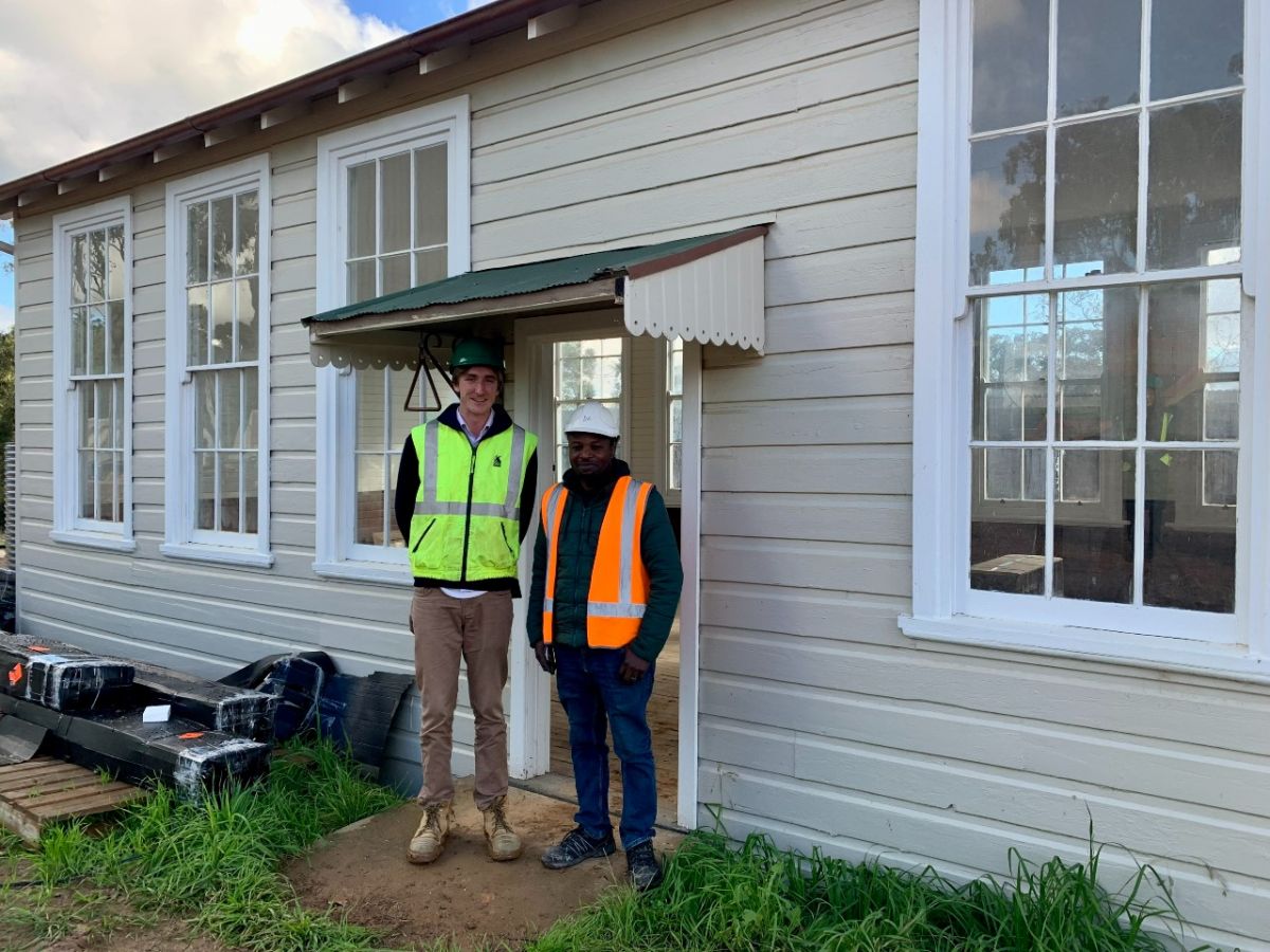 Pictured in front of the schoolhouse on the museum site at Willans Hill is Project Coordinator Henry Collie with contractor Ayodeji Temilola.