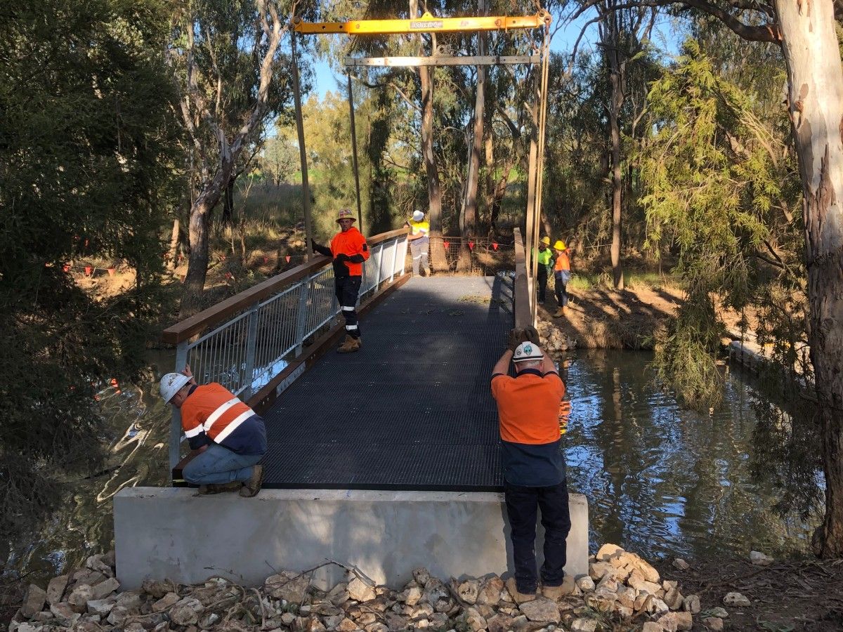 Contractors in hi-vis vests as footbridge is lowered into place