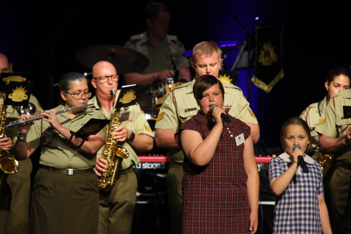 Two school girls sing with the Australian Army Band Kapooka