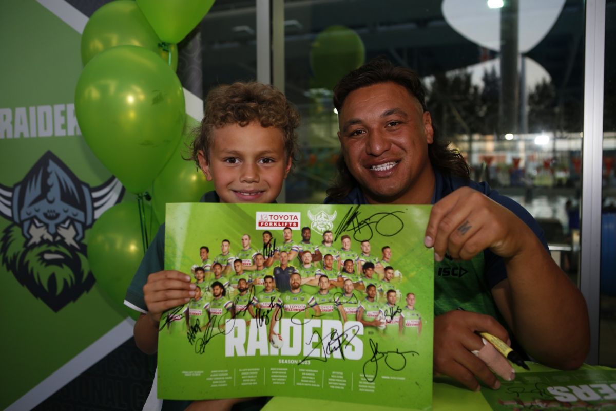 Young boy with Raiders player, holding up autographed poster