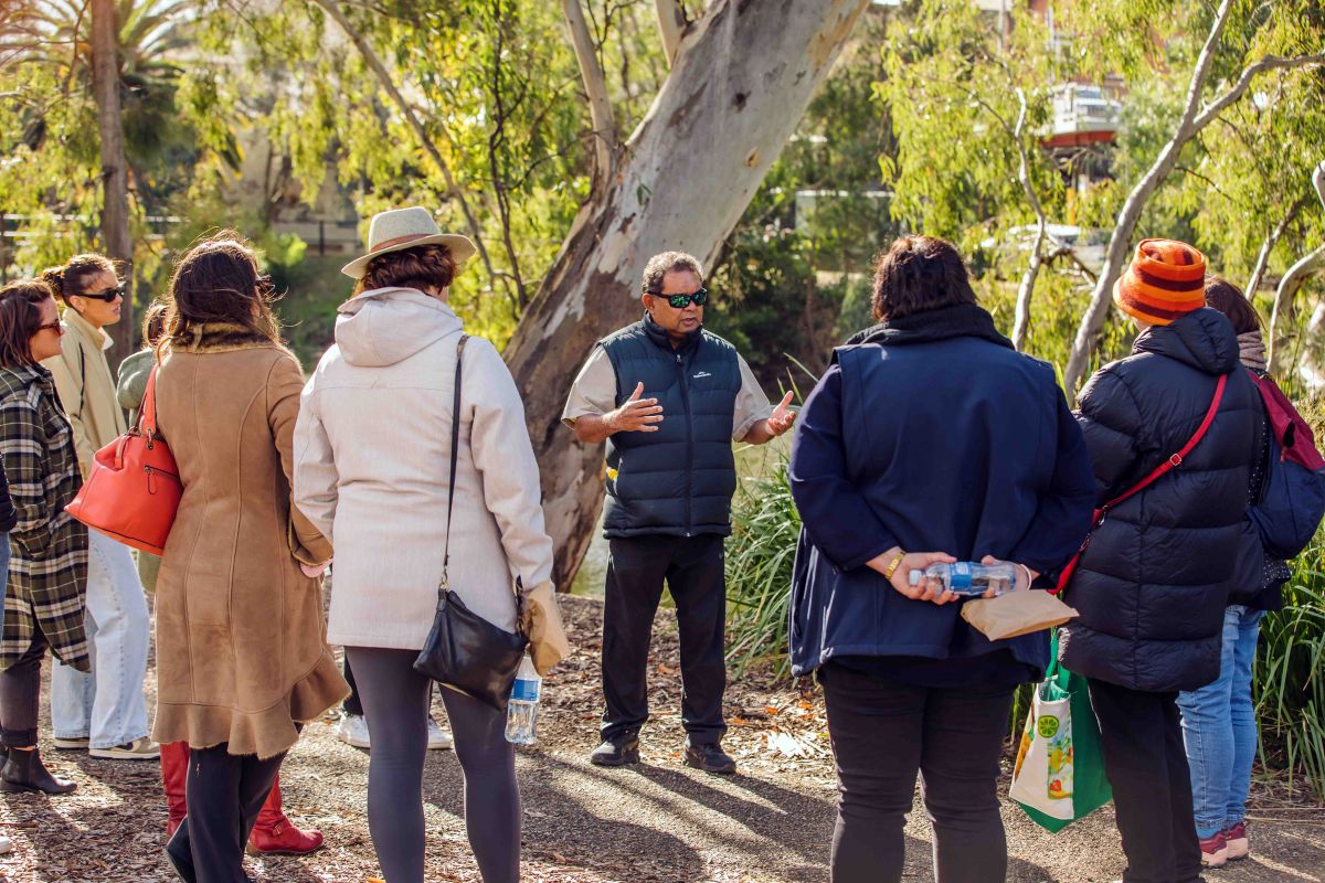Wiradjuri Elder leading a cultural walk through bushland, with group of people 