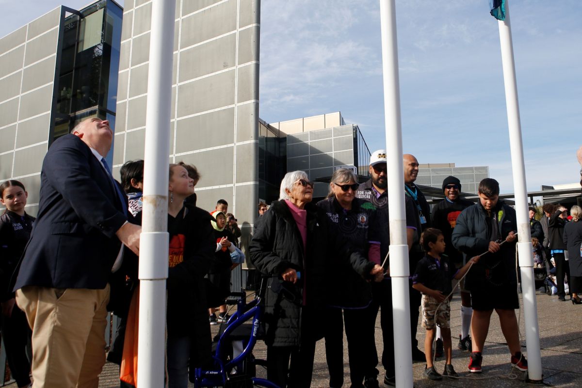 A group of people raising three flags. 