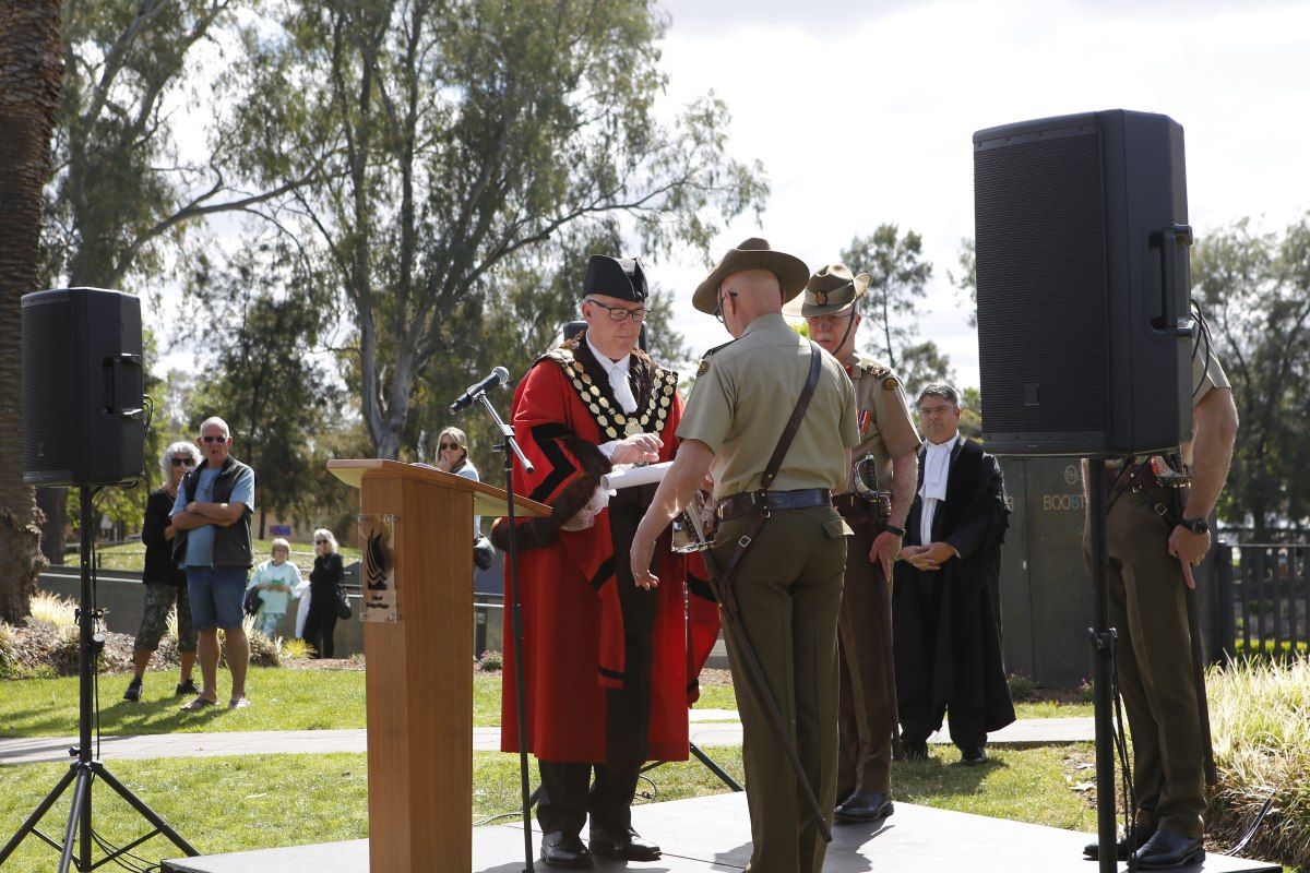 Mayor in formal robes hands scroll to an Army Officer