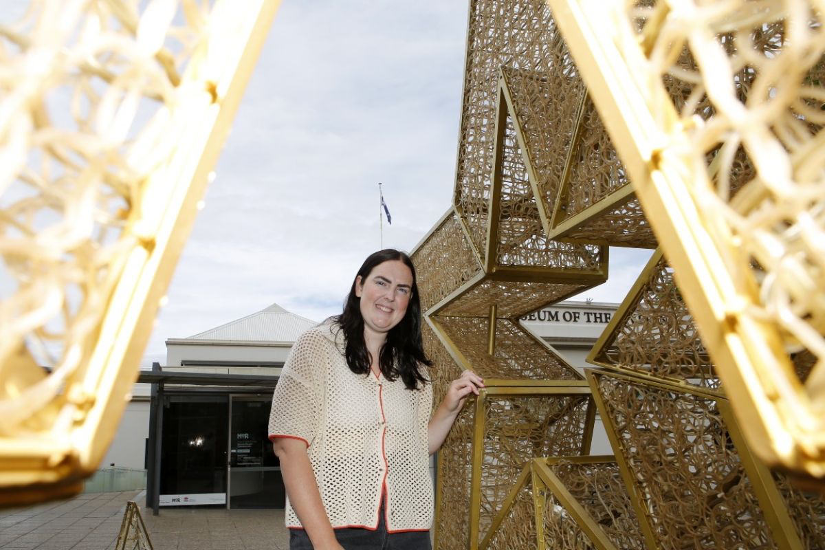 Woman standing next to light installation of Christmas stars