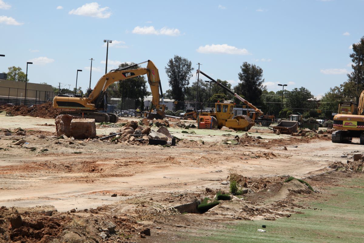 Heavy machinery demolishing a tennis court and clubhouse. 