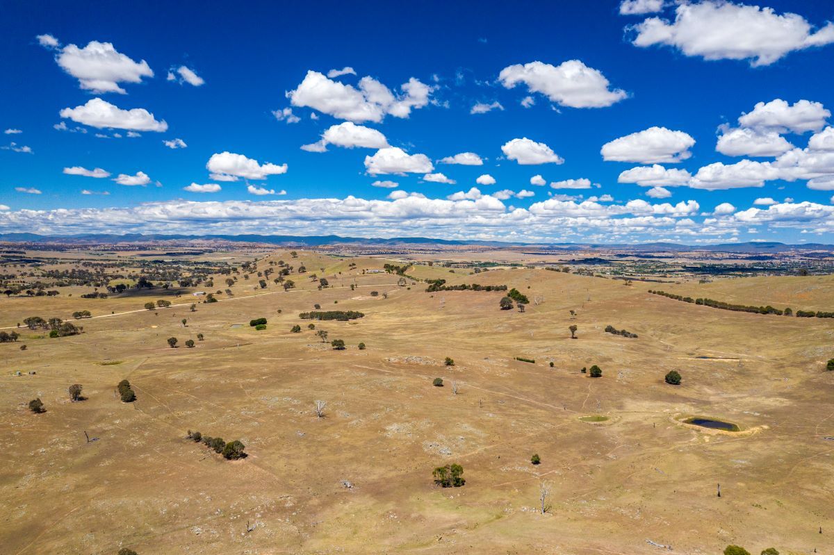 An ariel photograph of some dry rolling plains. The sky is blue with puffy clouds. 