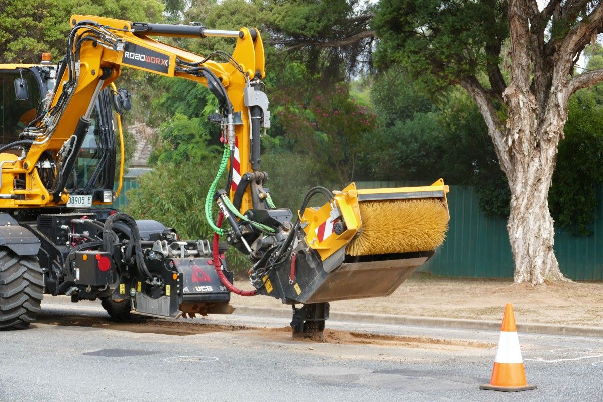 Pothole Pro machine using jackhammer attachment during pothole repair on suburban road.