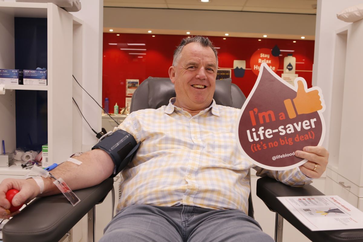 A man sits in a clinic donating blood. 