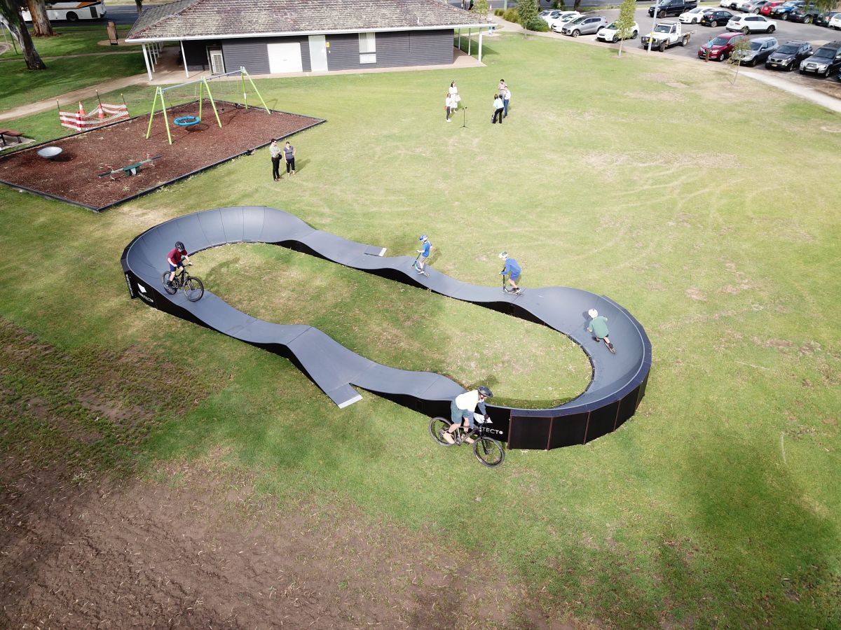 Scooter and bike riders on modular pump track in park