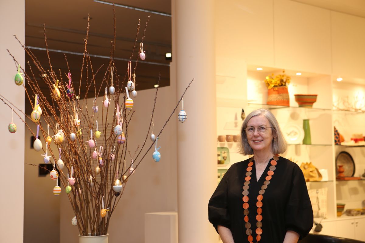 Woman standing next an Easter display with large twigs covered with decorated eggs