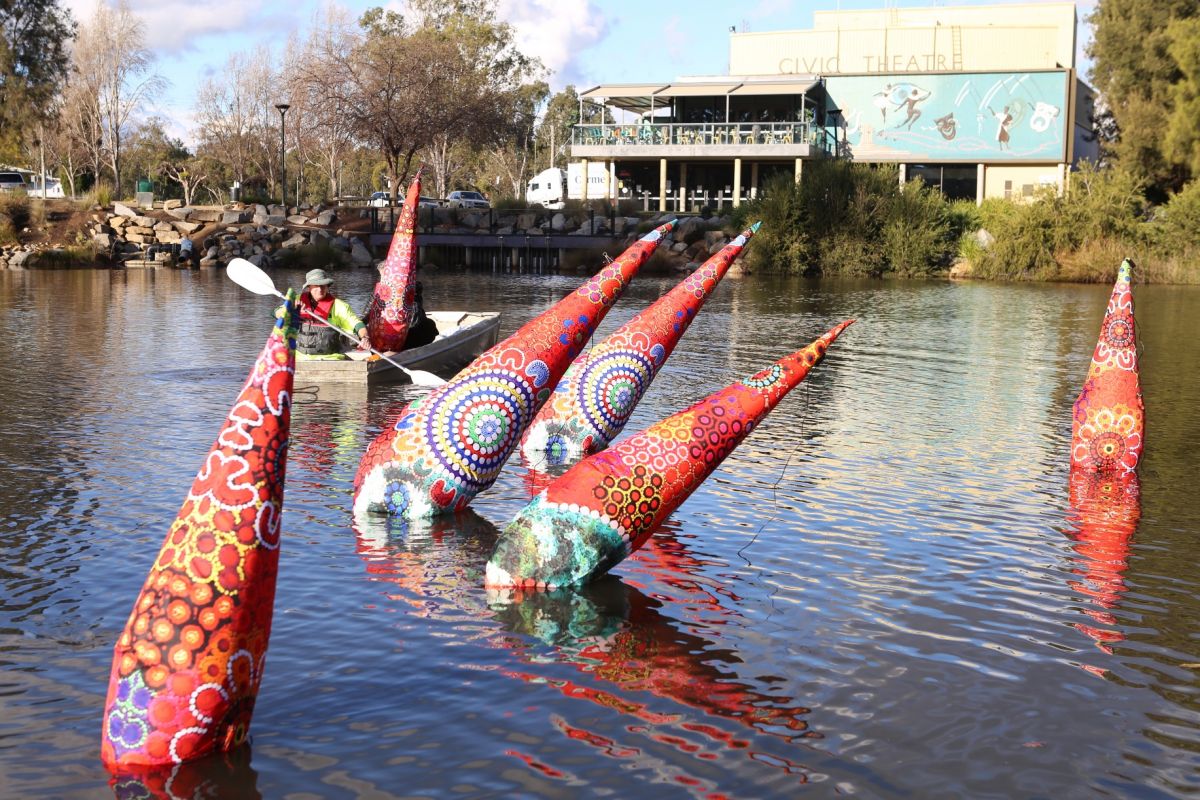 two men in dinghy installing floating inflatable artworks on lagoon