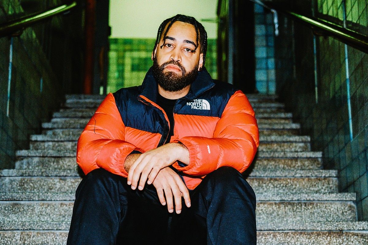 Man with beard in orange jacket sitting on steps