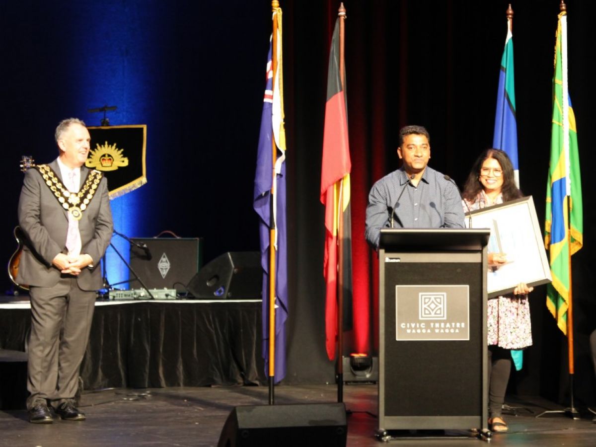 A man speaks at a lectern with a woman beside him