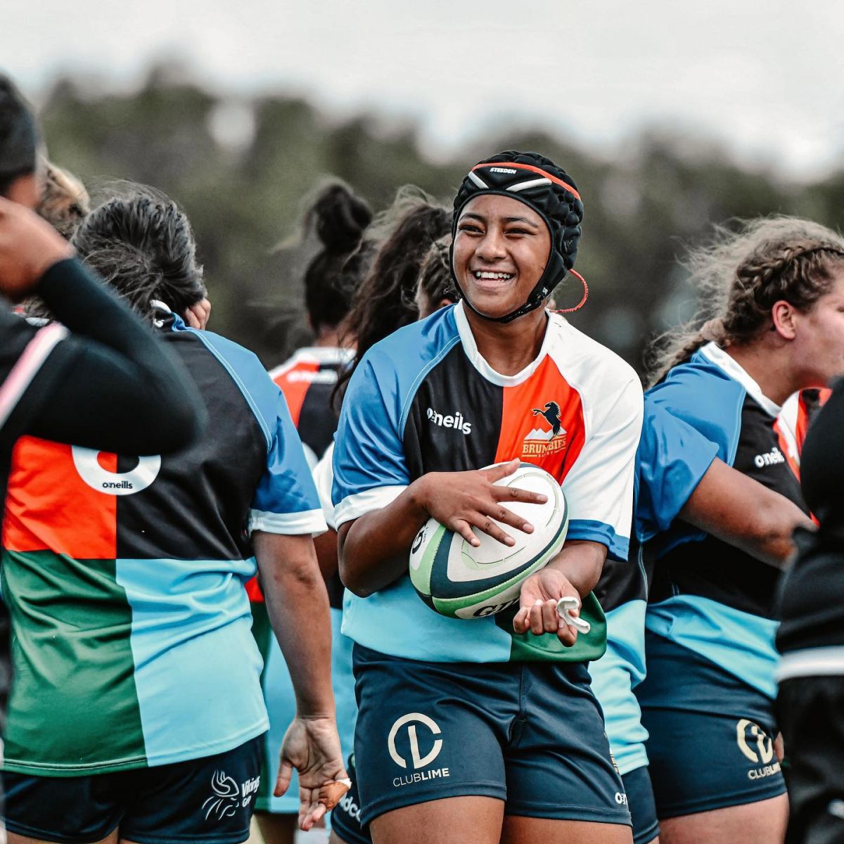 Young female Brumbies player clasping ball and smiling