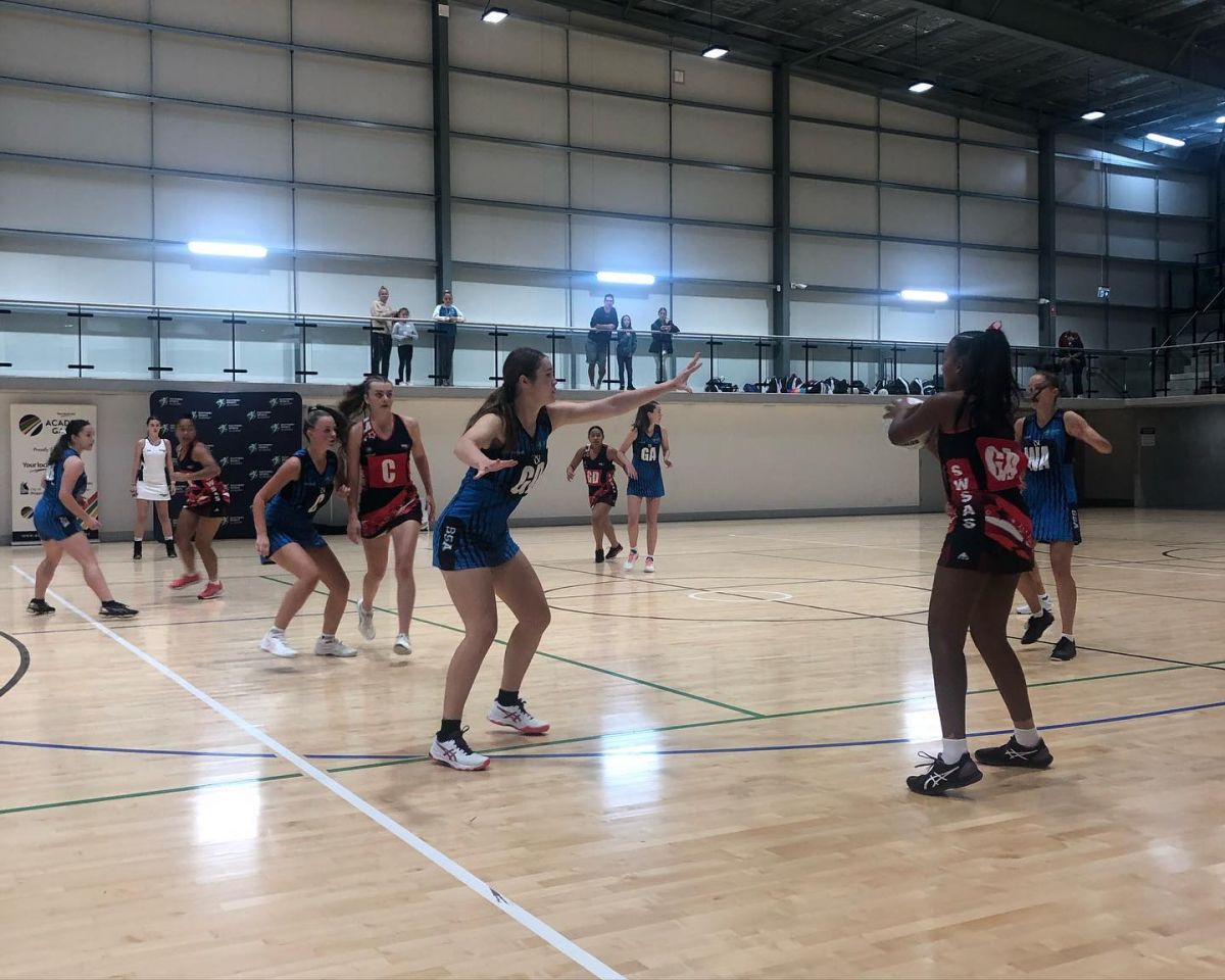 Young women playing netball indoors