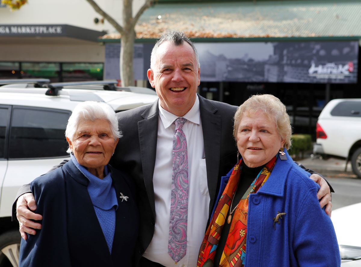 three people standing together smiling at the camera. 