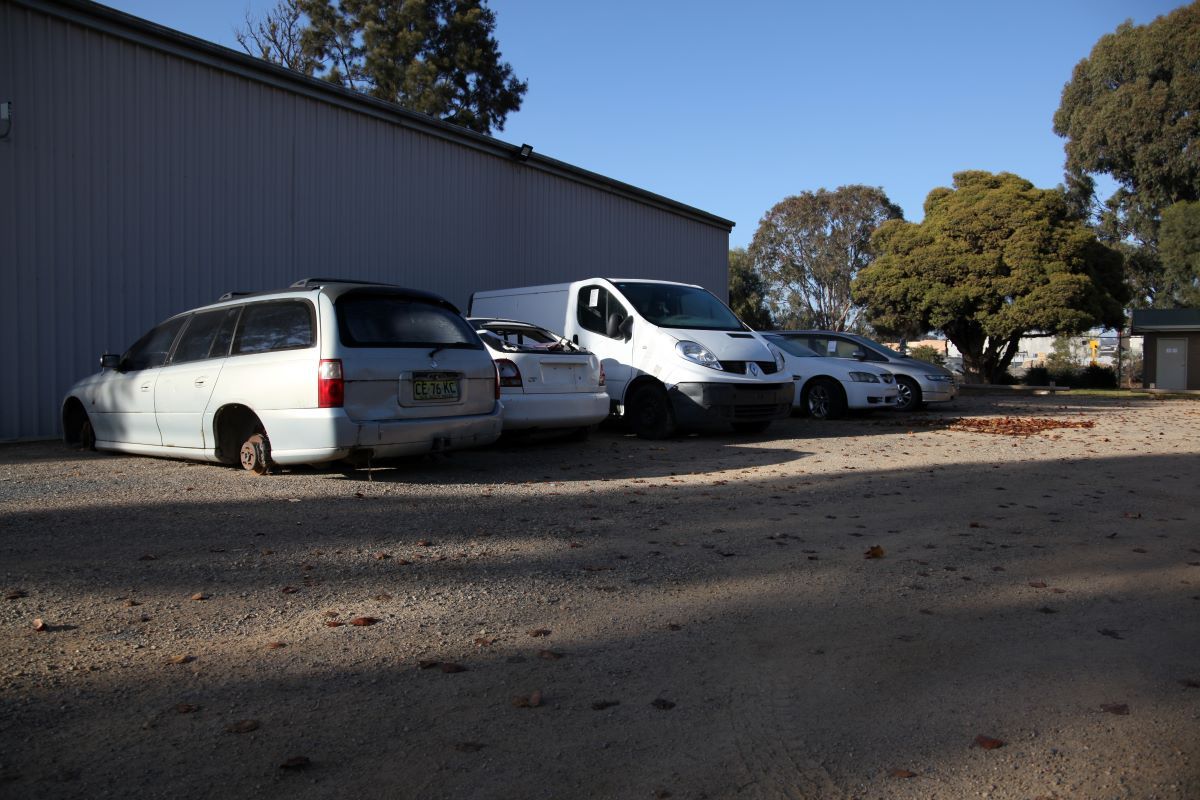 Line of vehicles next to a large shed.