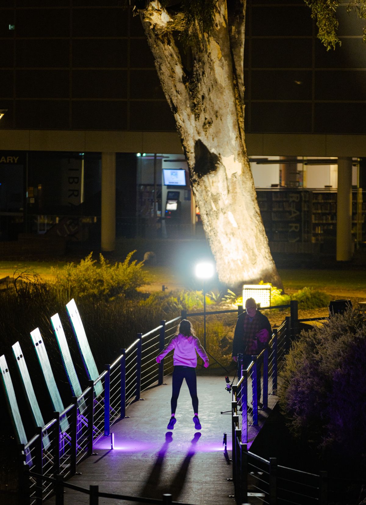 Local First Nations dancer Ivy Simpson with sound artist Peter Mcilwain recording dancing on the Wollundry Lagoon boardwalk at night time.