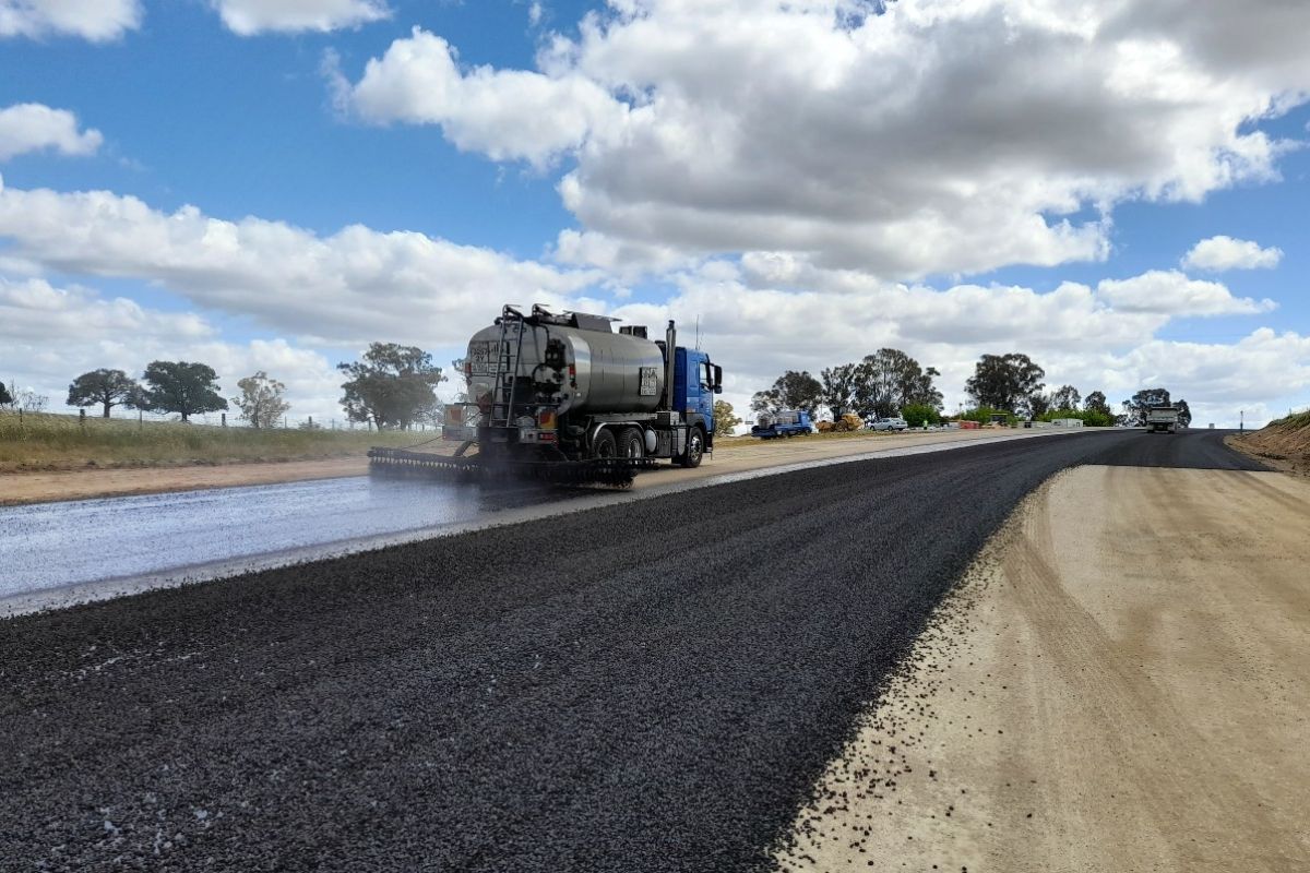 Bitumen truck applies seal on gravel on stretch of reconstructed road