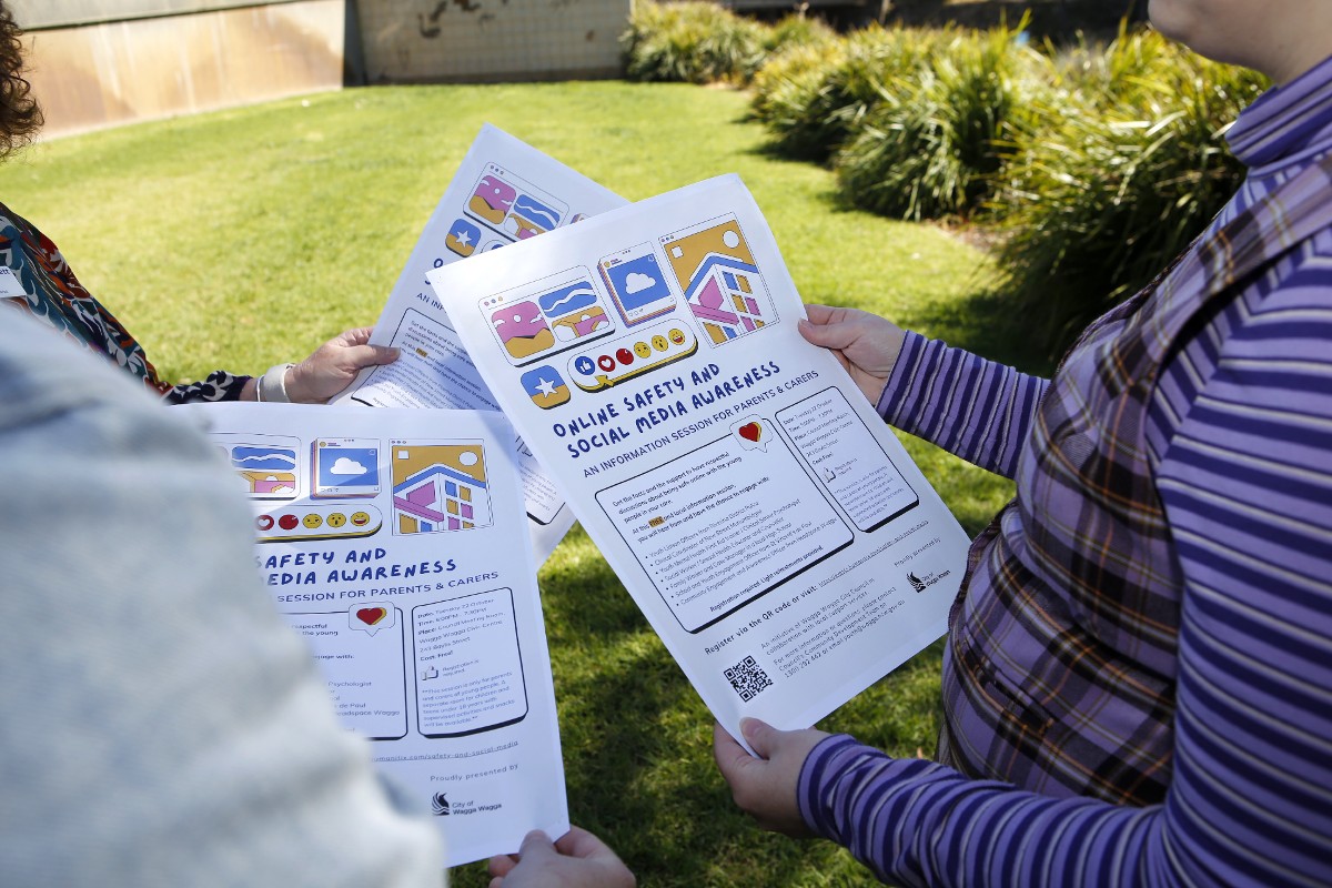 Close up of three Online Safety and Social Media Awareness session posters being held by three sets of hands.