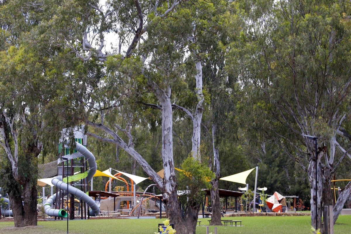 Playground with swings and towers in the background, with grassed park area in the foreground