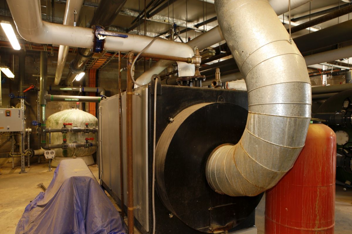 Large rectangular gas water heating containers with large pipes going into and out of the container.