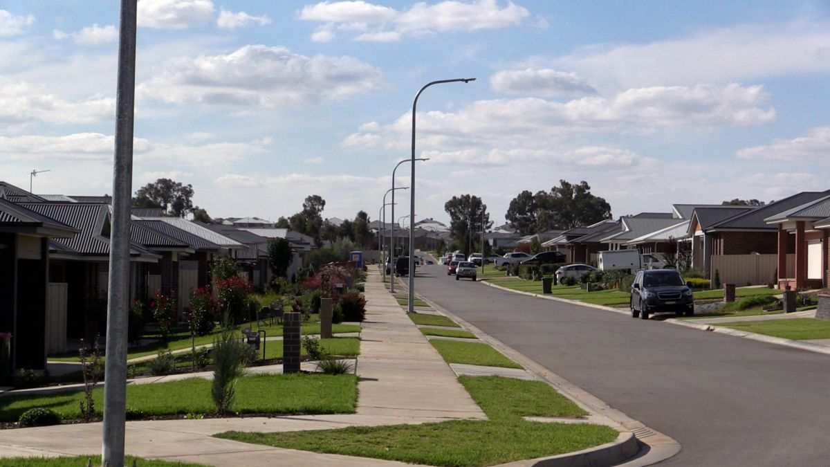 Houses, nature strips, street, cars on road and in driveways