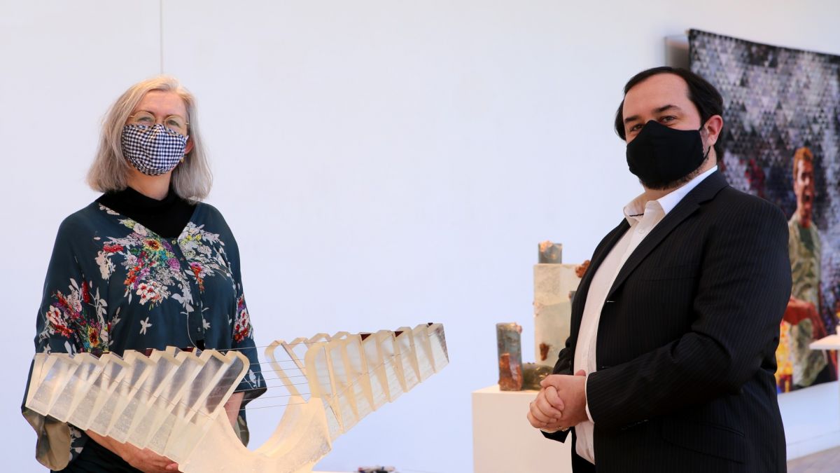 Man and woman standing beside glass art on display