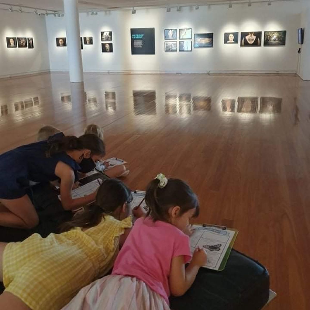 Four young girls lying on floor painting insects