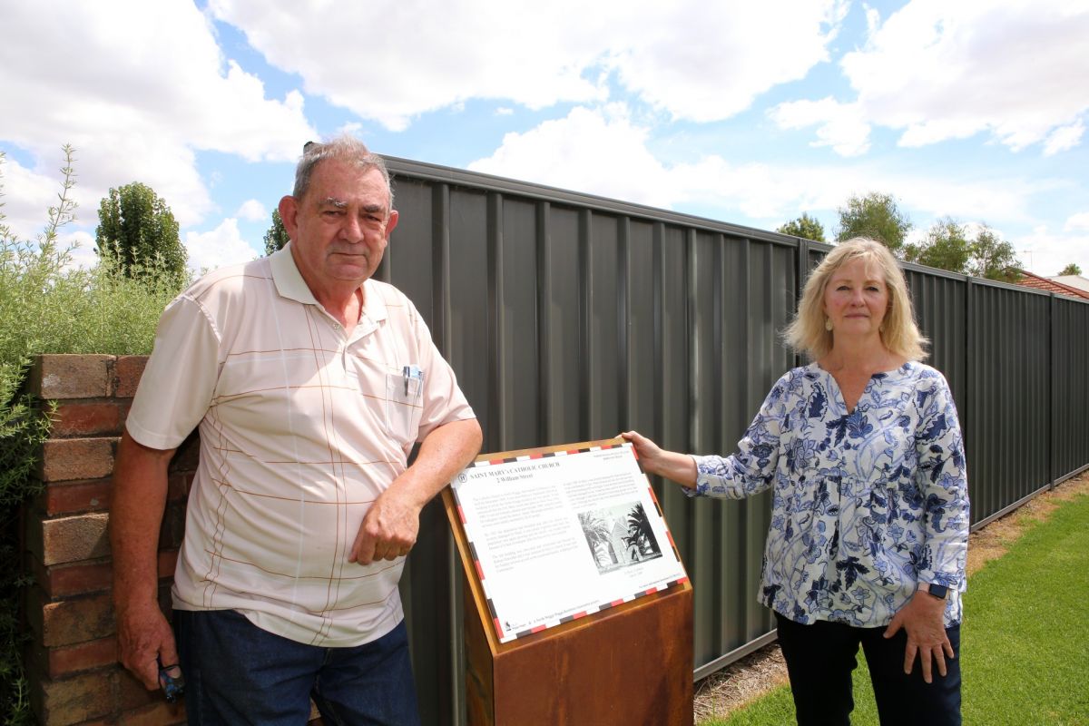 Man and woman standing on either side of heritage sign