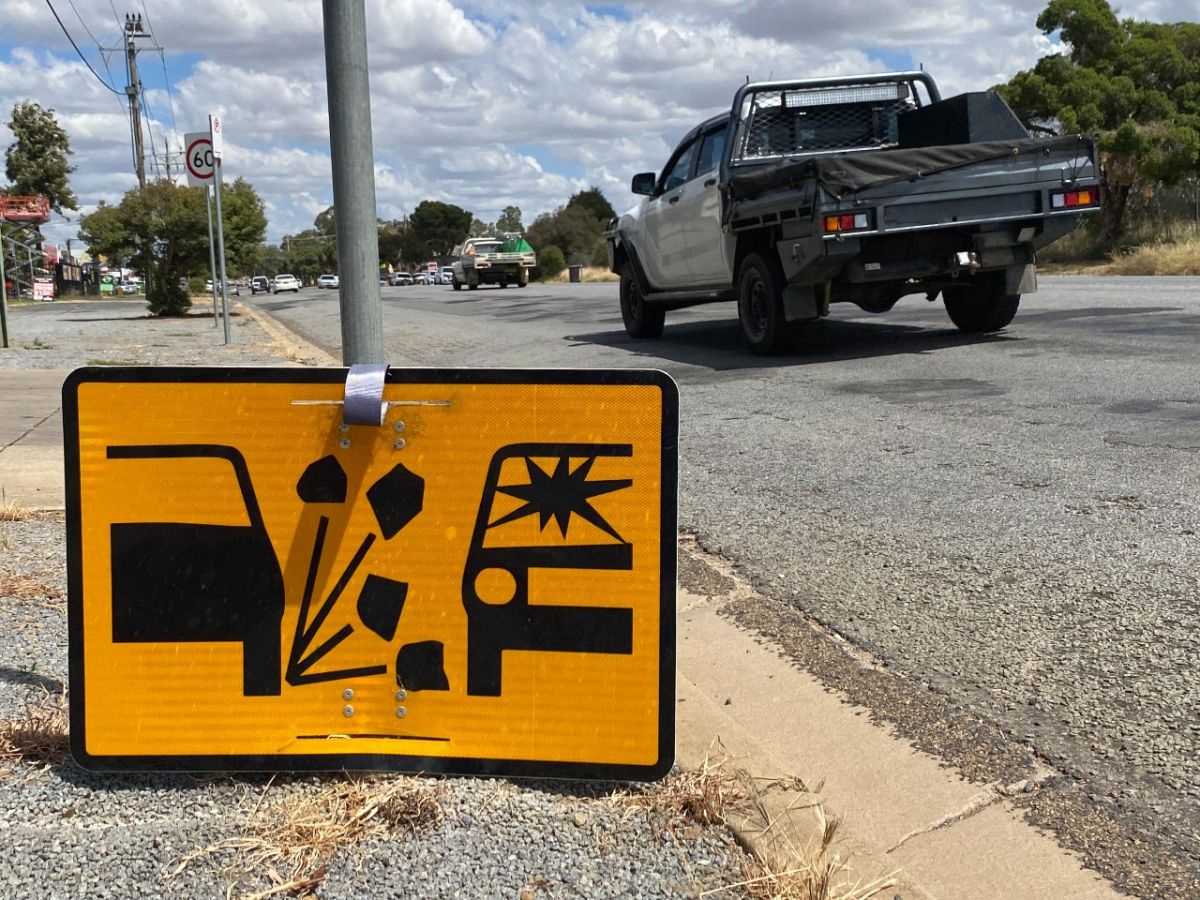 A utility vehicle drives past a road sign warning drivers of windscreen damage